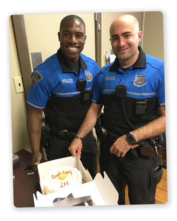 Two law enforcement officers (LEO) with a cake that says "Good Luck, Lee"