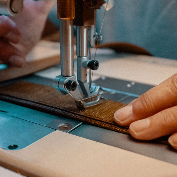 A close up of someone crafting a collar by hand in the USA with a sewing machine